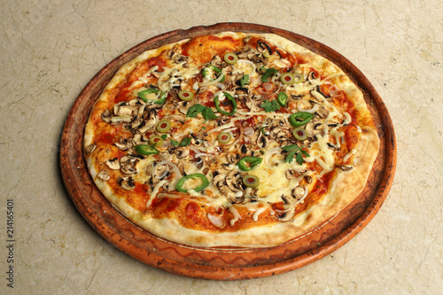 Vegetarian pizza with onions, peppers olives and cheese, top view on a restaurant table