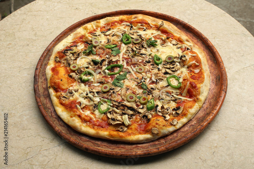 Vegetarian pizza with onions, peppers olives and cheese, top view on a restaurant table