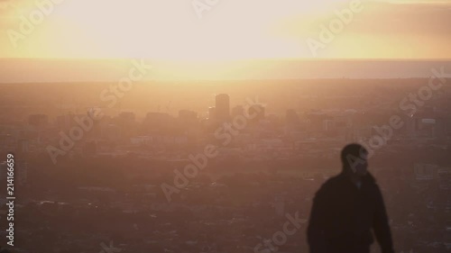 Man walking up hill during sunset overlooking city