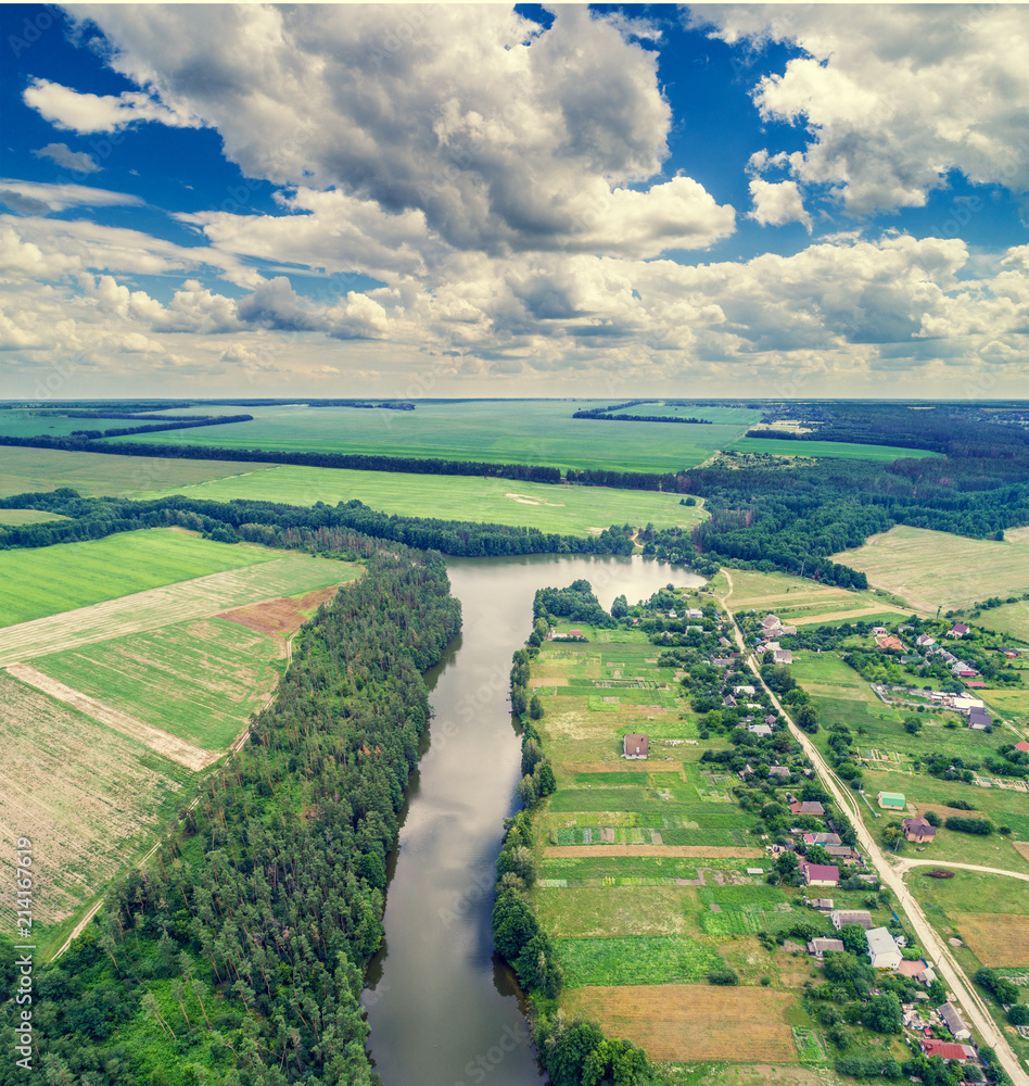 Fototapeta premium Aerial view of countryside and river with a beautiful sky. Forest and village along the river