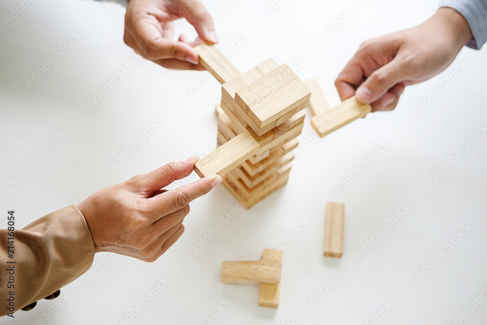 Hand of business people planning, risk and strategy in business.Businessman gambling placing wooden block on a tower. Hand of business people planning, risk and strategy in business.Businessman gambling placing wooden block on a tower.