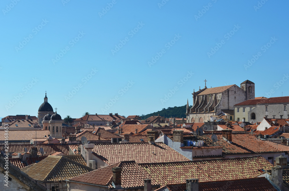 The terracotta tiles on the roofs of Dubrovnik. The cathedral stands to one side. The sky is clear and blue sky.