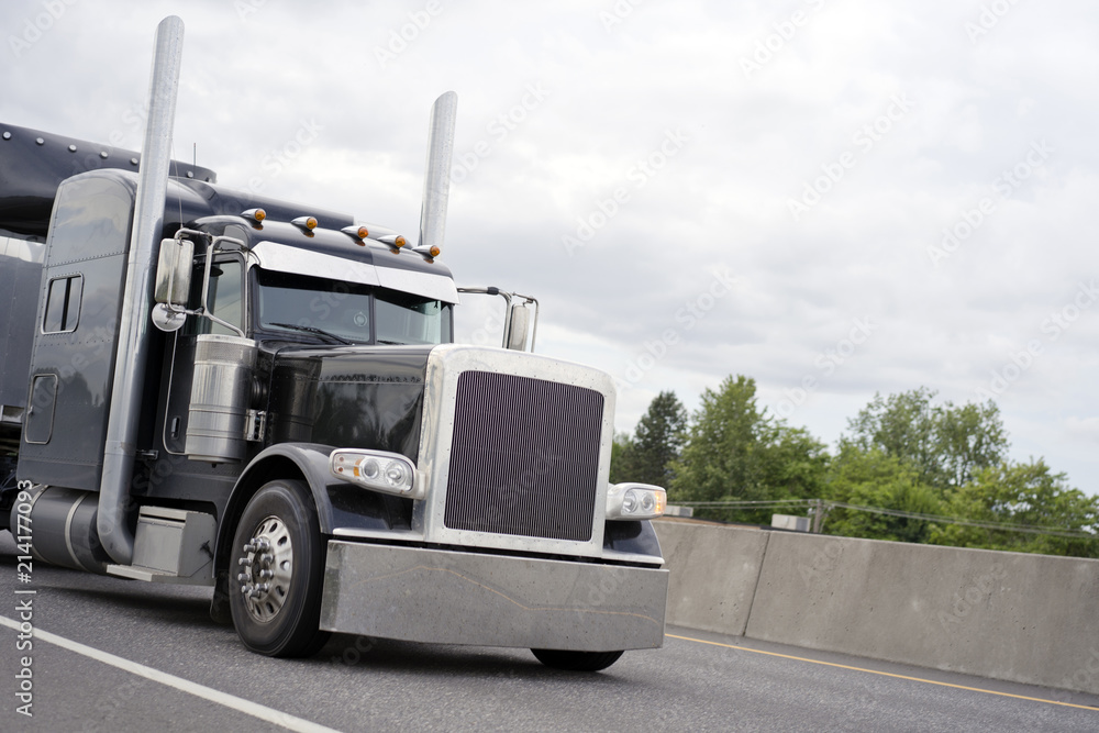 Black stylish classic big rig semi truck running on road Black stylish classic big rig semi truck running on road