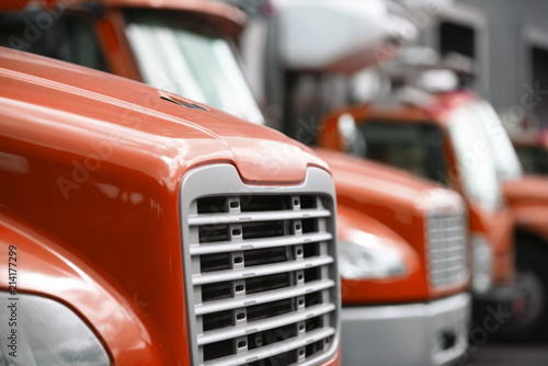 Middle sized rigs semi trucks standing in row in warehouse dock for loading cargo