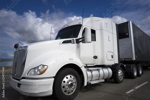 White big rig semi truck with black tented semi trailer transporting commercial cargo on the road photo