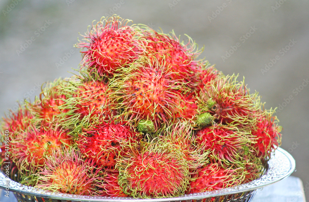 Fresh red rambutan,Tropical fruit in white plate on table background Fresh red rambutan,Tropical fruit in white plate on table background