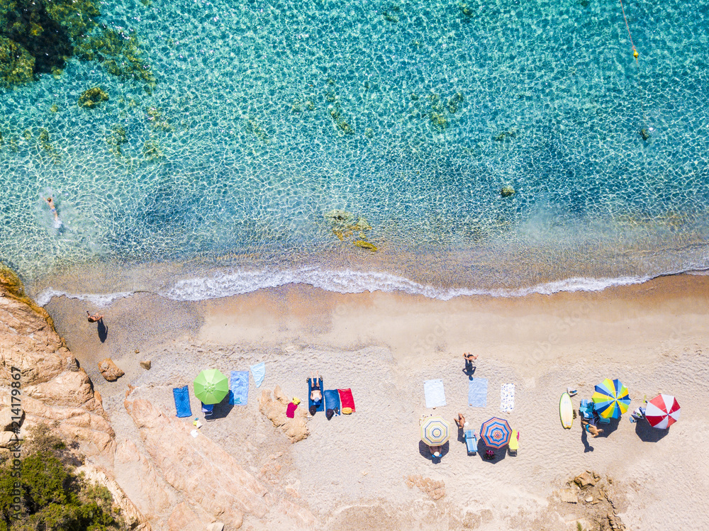Aerial view of an emerald and transparent Mediterranean sea with a white beach full of beach umbrellas and tourists who relax and take a bath.Sardinia, Italy.
