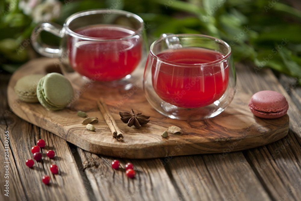 Φωτογραφία Close-up of delicious macarons with berries and cups of red tea on wooden backgr