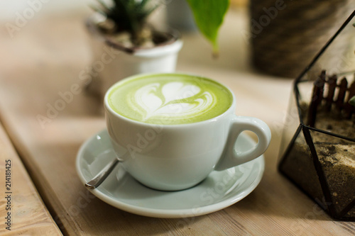 Green tea matcha latte art with succulent  cropped at an angle at a coffee shop cafe on wooden table 