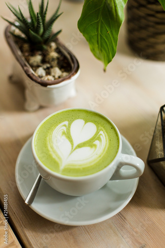 Green tea matcha latte art with succulent  cropped at an angle at a coffee shop cafe on wooden table 