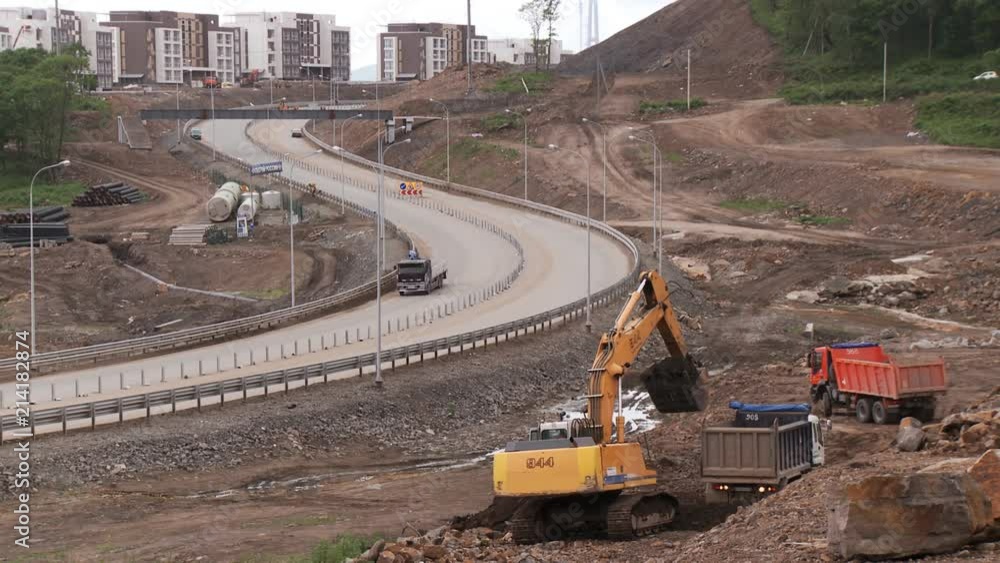 Empty trucks drive up to the yellow excavator for a ground, which it must remove from the construction site Empty trucks drive up to the yellow excavator for a ground, which it must remove from the construction site