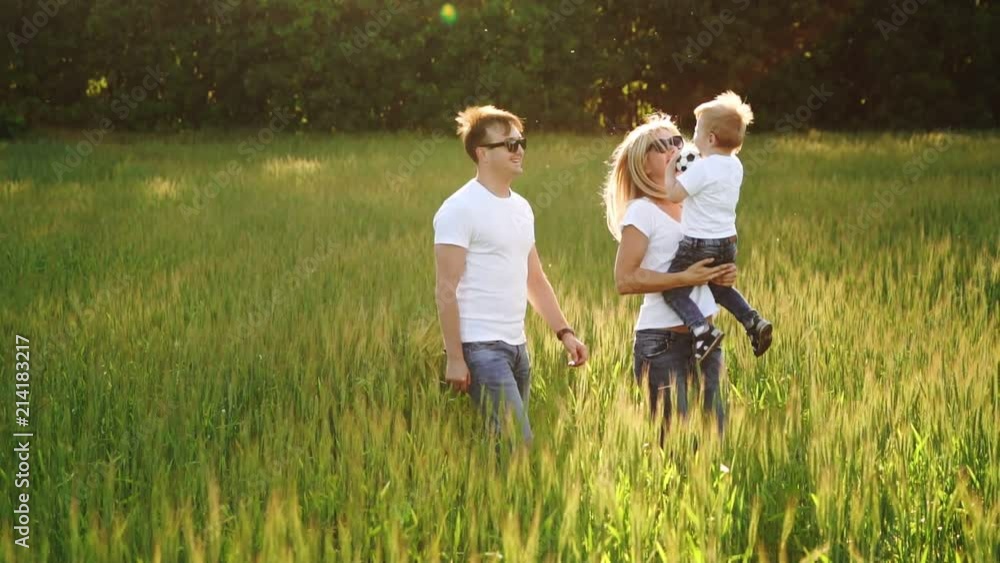 Family Walking In Field Carrying Young Baby Son Family Walking In Field Carrying Young Baby Son