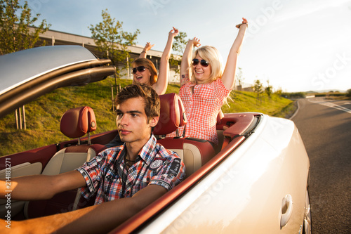 junger Mann fährt Cabrio mit Freundinnen auf der Rückbank