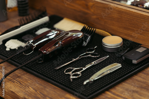 close-up view of set of professional barber tools on wooden shelf in barbershop