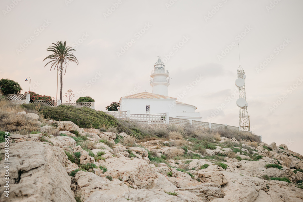 White lighthouse on the rocky hill in Spain