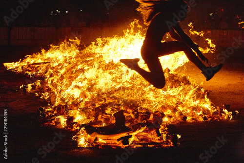 Summer solstice celebration in Spain. Woman jump. Fire flames photo