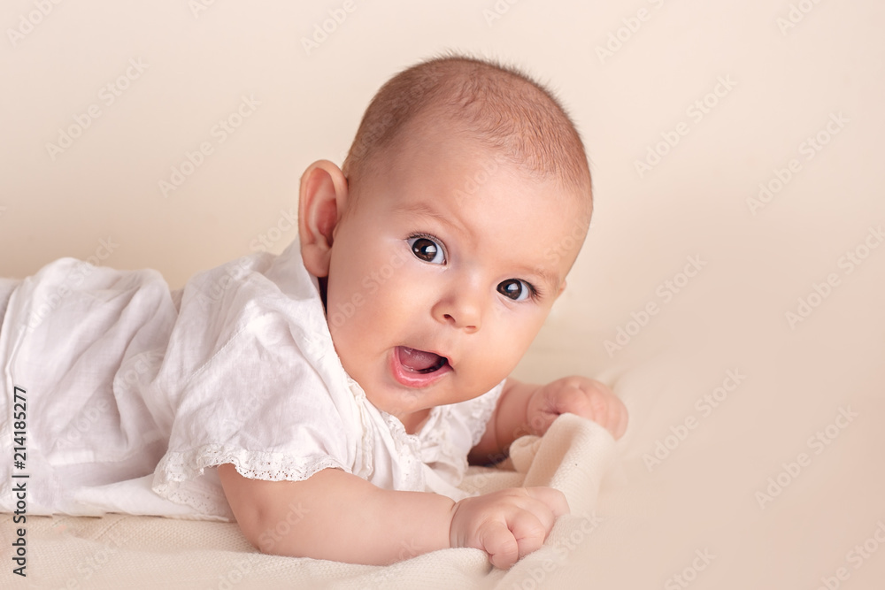 Cute funny baby with big beautiful eyes lying on a white blanket Cute funny baby with big beautiful eyes lying on a white blanket