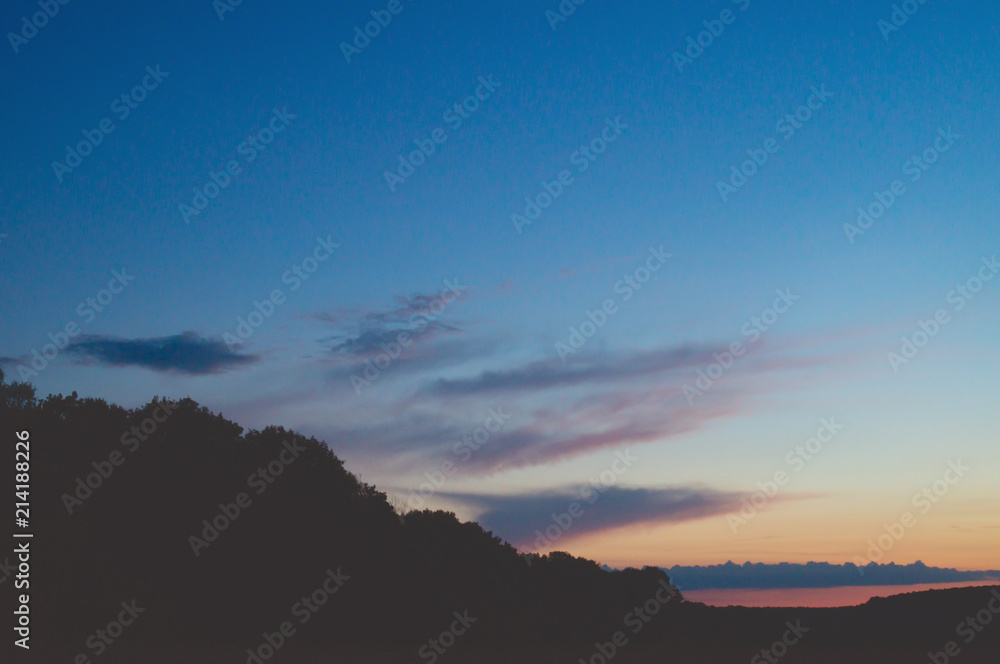 Obraz premium Picturesque evening sky after sunset over dark dense forests
