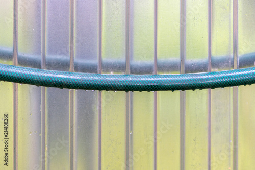 Green, garden hose against the background of a metal wall, after a rain photo