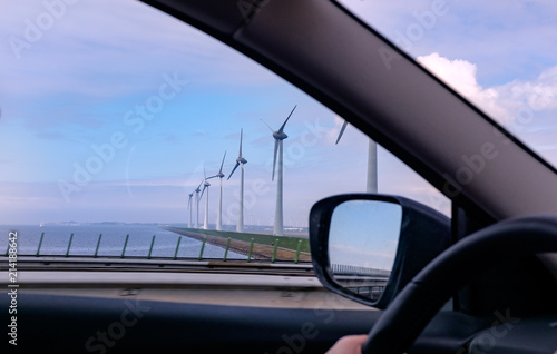 Wind turbine generating electricity on blue sky with clounds,Windmills for electric power ecology concept. View of car windows