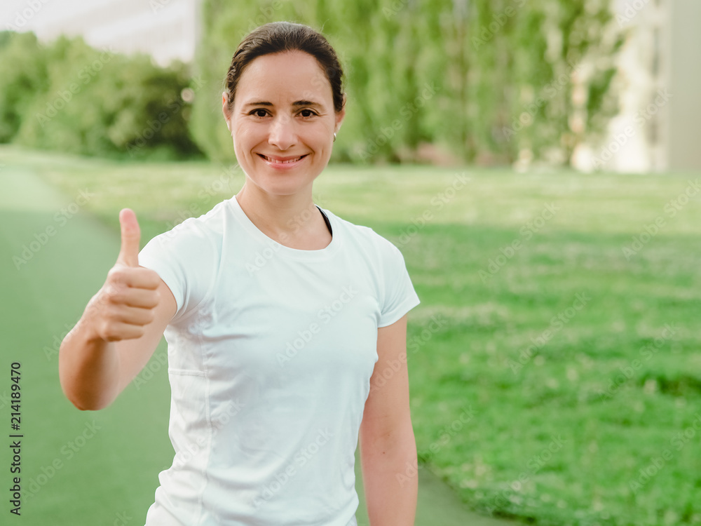 happy smiling femal Fitness Coach in white sportswear making Thumbs up outdoor in green nature happy smiling femal Fitness Coach in white sportswear making Thumbs up outdoor in green nature