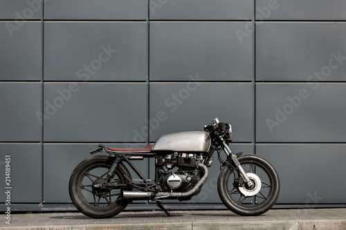 Old motorbike parking near gray wall of finance building. Everything is ready for having fun driving the empty road on a motorcycle tour journey. City hobby. Space for your individual text.