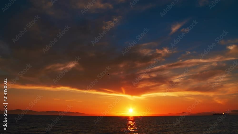 A beautiful sunset in the clouds, on the surface of the ocean, the waves shine brightly in the sun, far away is the mountains in light evening haze. Color correction options A beautiful sunset in the clouds, on the surface of the ocean, the waves shine brightly in the sun, far away is the mountains in light evening haze. Color correction options