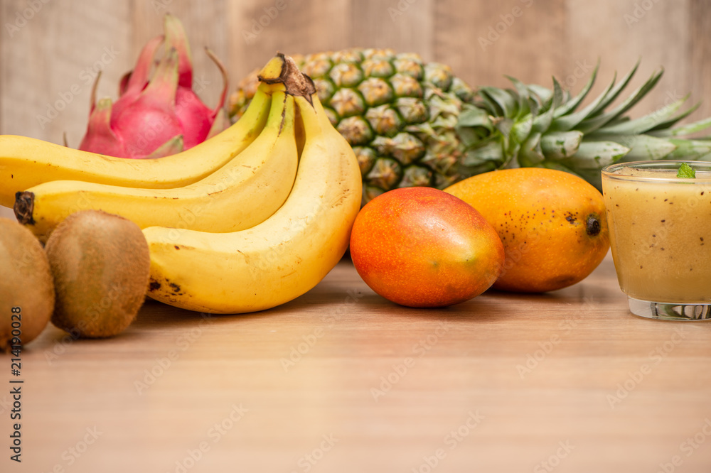 Tropical fresh fruit set and juice smoothies isolated with wooden background Tropical fresh fruit set and juice smoothies isolated with wooden background