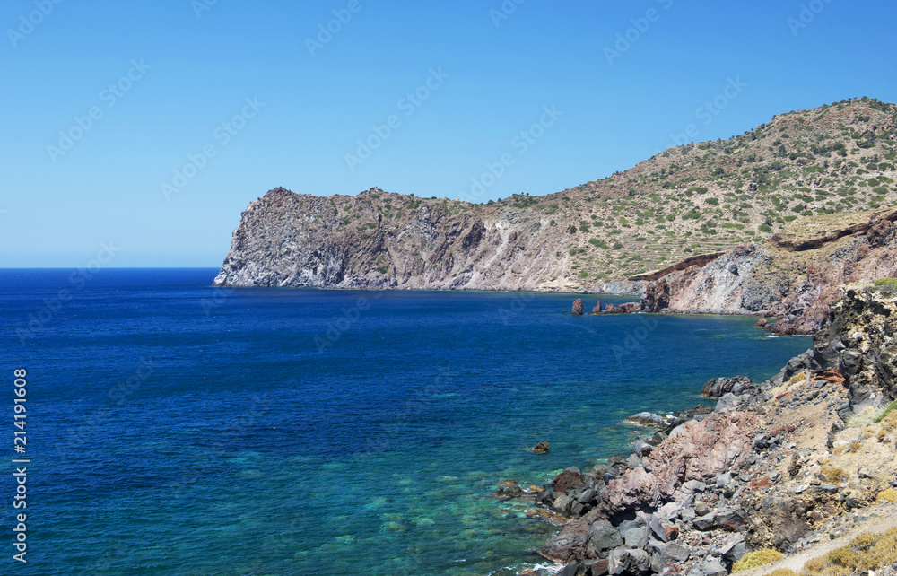 Blue sea and the characteristic caves of Cala Luna, a popular beach in Sardinia,Italy,view of Cala Luna beach with the crystal sea and mountains with mist smog background on summer,sardinian landscape