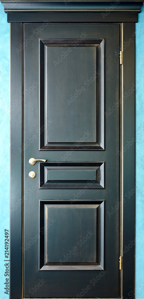 Wooden interior black and golden door of ebony with brass metal handle on blue Wooden interior black and golden door of ebony with brass metal handle on blue