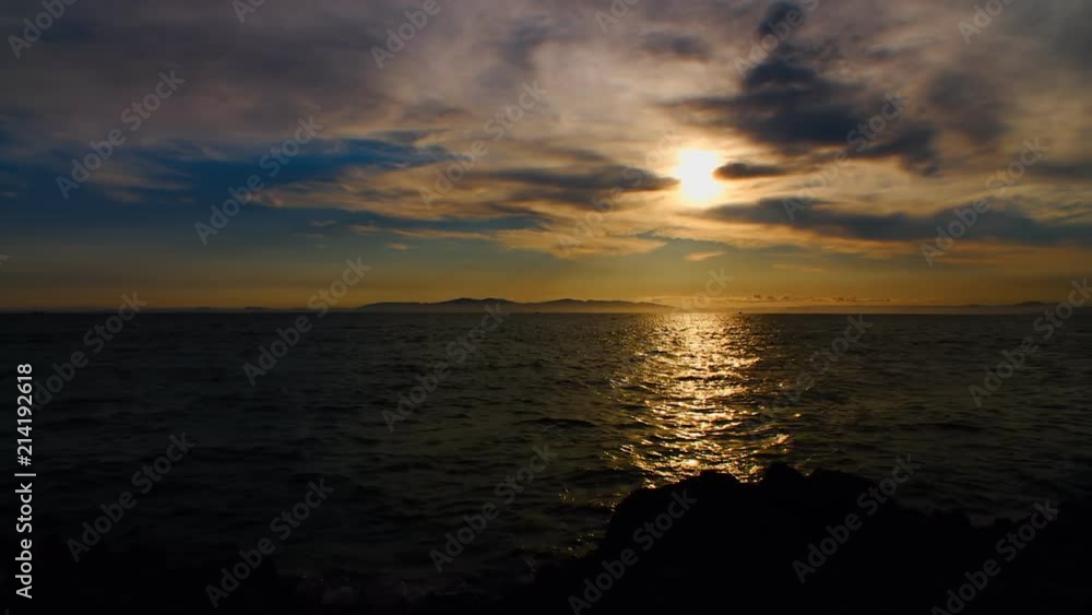 A beautiful sunset in the clouds, on the surface of the ocean, the waves shine brightly in the sun, far away is the mountains in light evening haze. Color correction options A beautiful sunset in the clouds, on the surface of the ocean, the waves shine brightly in the sun, far away is the mountains in light evening haze. Color correction options