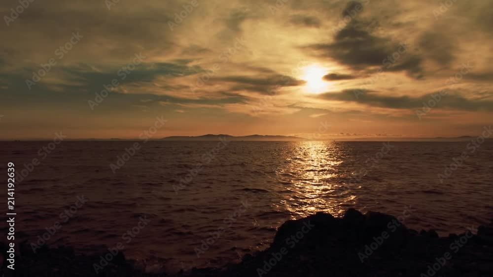 A beautiful sunset in the clouds, on the surface of the ocean, the waves shine brightly in the sun, far away is the mountains in light evening haze. Color correction options A beautiful sunset in the clouds, on the surface of the ocean, the waves shine brightly in the sun, far away is the mountains in light evening haze. Color correction options