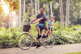 Smiling father with boy on bicycles having fun in park. Family sport and healthy lifestyle.