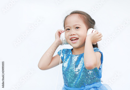 Cute little girl in bright dress listening music with headphones isolated on white background.