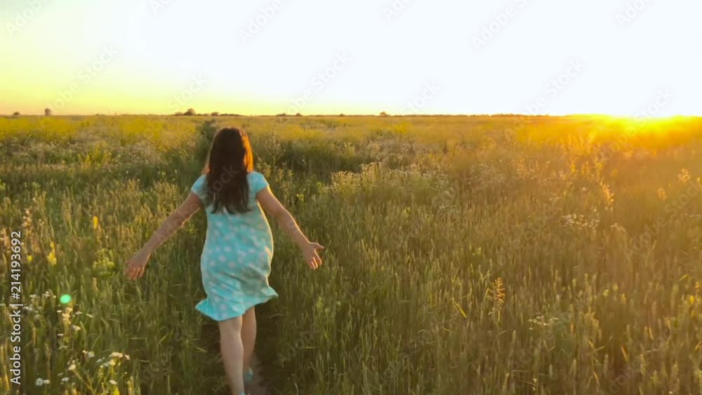 Beauty girl running on green wheat field over sunset sky. Freedom concept. Wheat field in sunset Beauty girl running on green wheat field over sunset sky. Freedom concept. Wheat field in sunset