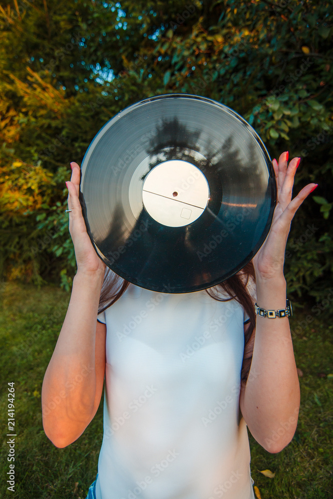 Girl holding a vinyl record in her hands, covering her face