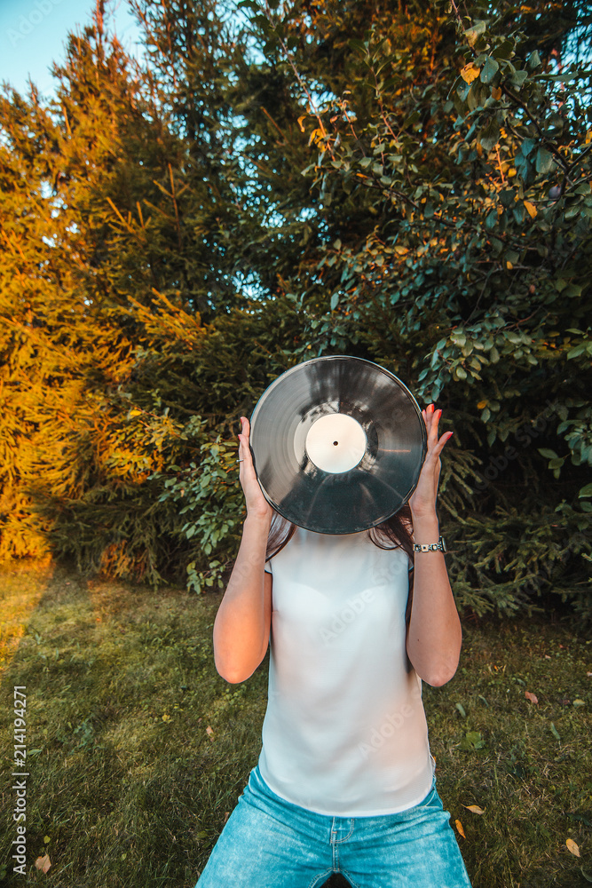 Girl holding a vinyl record in her hands, covering her face