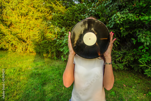 Girl holding a vinyl record in her hands, covering her face