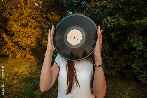 Obraz na płótnie Girl holding a vinyl record in her hands, covering her face w salonie