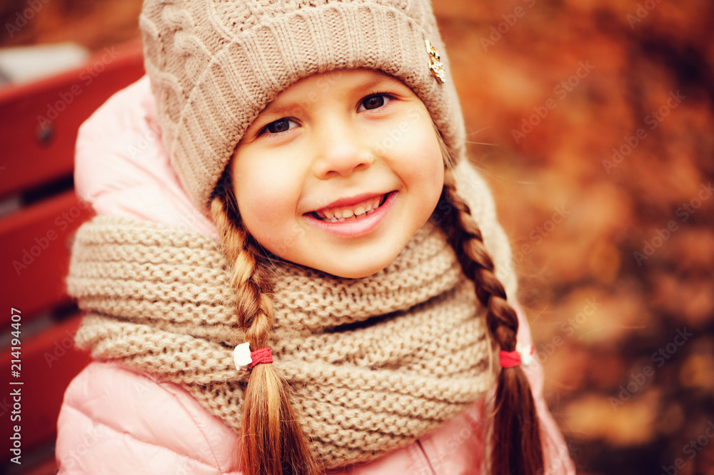 autumn close up portrait of happy little child girl enjoying the walk in sunny park in warm knitted hat and scarf autumn close up portrait of happy little child girl enjoying the walk in sunny park in warm knitted hat and scarf