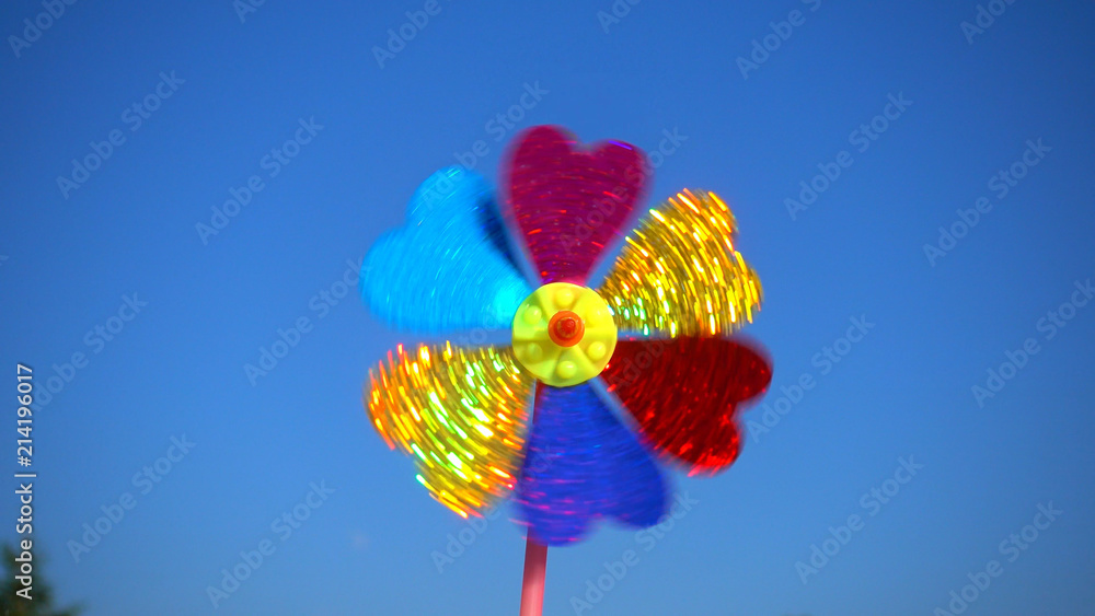 Spinning toy, children windmill against blue sky.