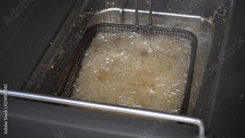 Chips are fried in boiling oil. Top view of the grid with French potatoes, the process of cooking.