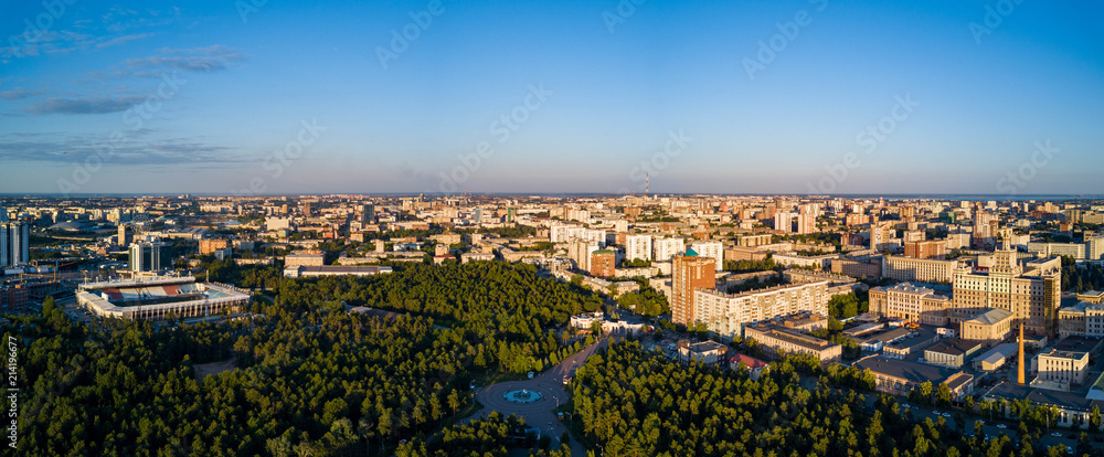 Fototapeta premium Panoramic drone view of Chelyabinsk city, huge park with mixed forest in the city center and college campus, sunny evening in the capital of South Ural, Russia
