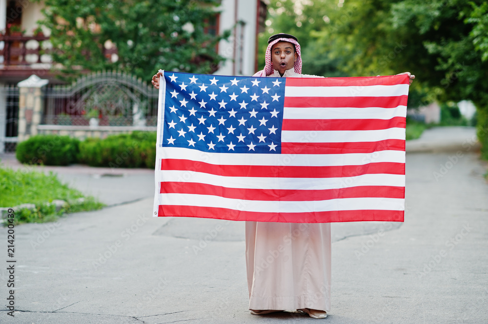 Middle Eastern arab man posed on street with USA flag. America and Arabian countries concept.