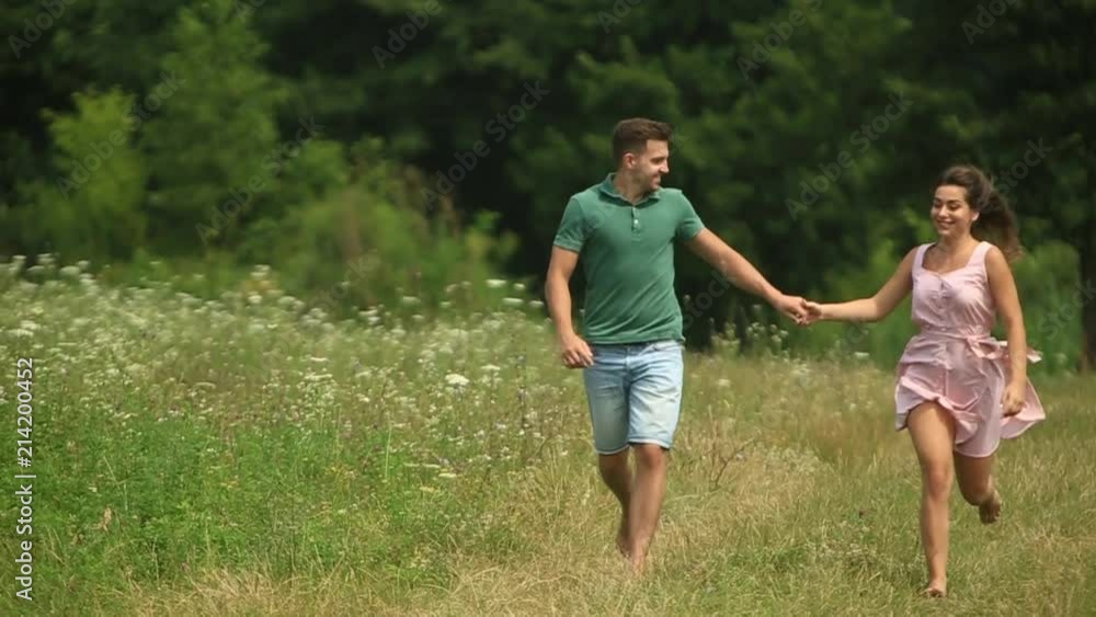 Male and female run togeter in field. Romantic atmosphere Male and female run togeter in field. Romantic atmosphere