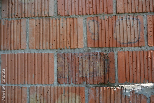 Stylish corrugated red clay bricks, brickwork with gray cement as construction work of builders