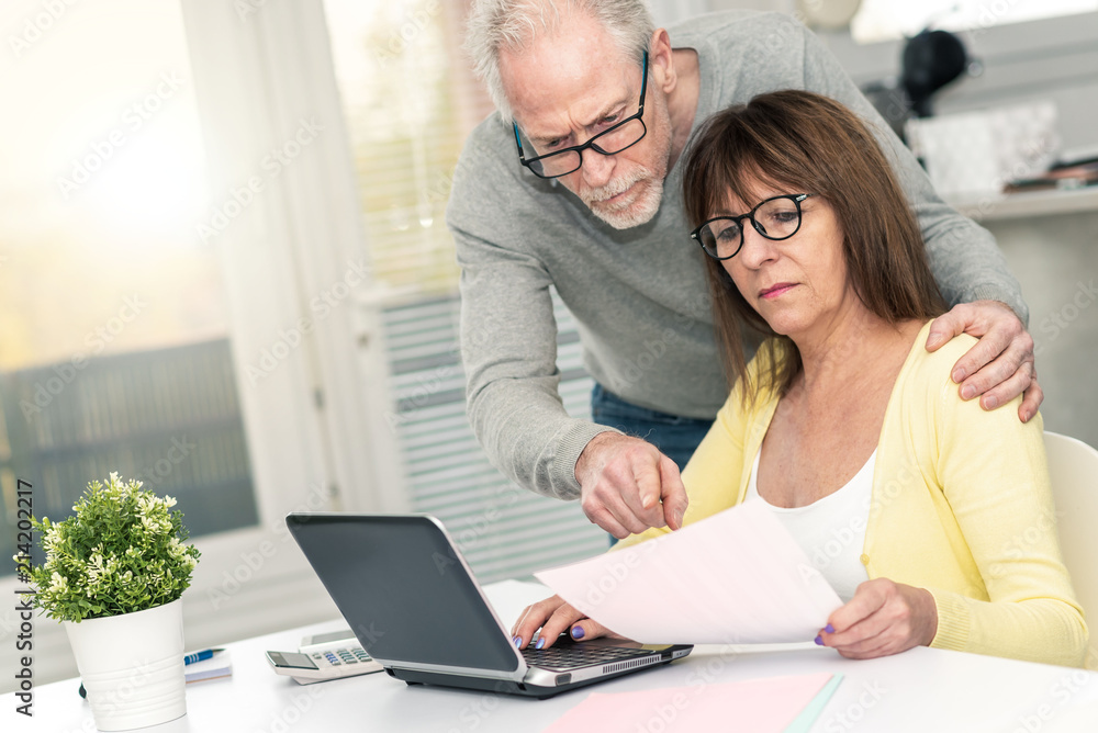 Senior couple checking financial document, light effect Senior couple checking financial document, light effect