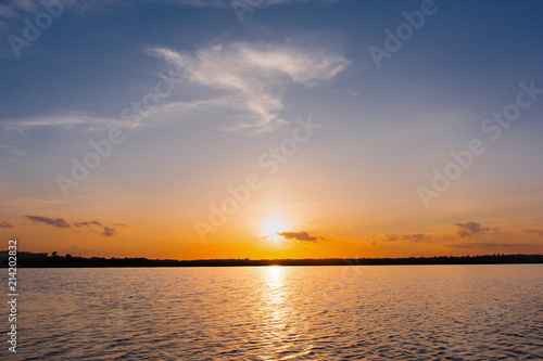Sunset in the lake. beautiful sunset behind the clouds above the over lake landscape background. dramatic sky with cloud at sunset © Achira22