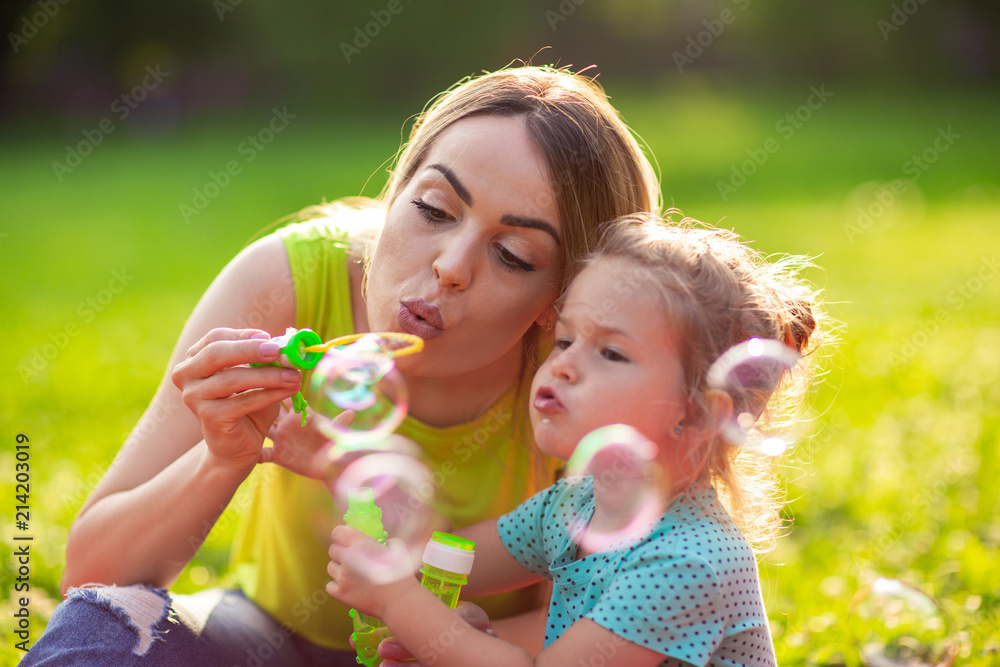 Female child blows soup foam and make bubbles with her mother in nature. Female child blows soup foam and make bubbles with her mother in nature.
