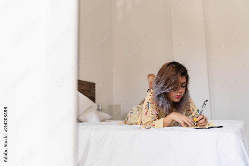 Left handed lady writing and lying on bed Left handed lady writing and lying on bed